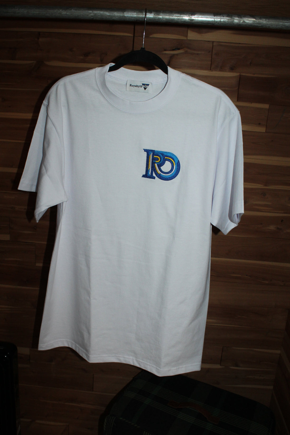R10 white embroidered t-shirt with blue and gold logo, minimalist luxury fashion piece representing quiet luxury and timeless wardrobe essentials.