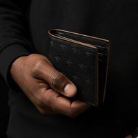 Close-up of a hand holding a structured black leather wallet illustrating intentional carry and reduced daily friction.