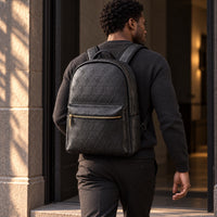 A man wearing the black R10 Leão Branco backpack moves through a shaded doorway.