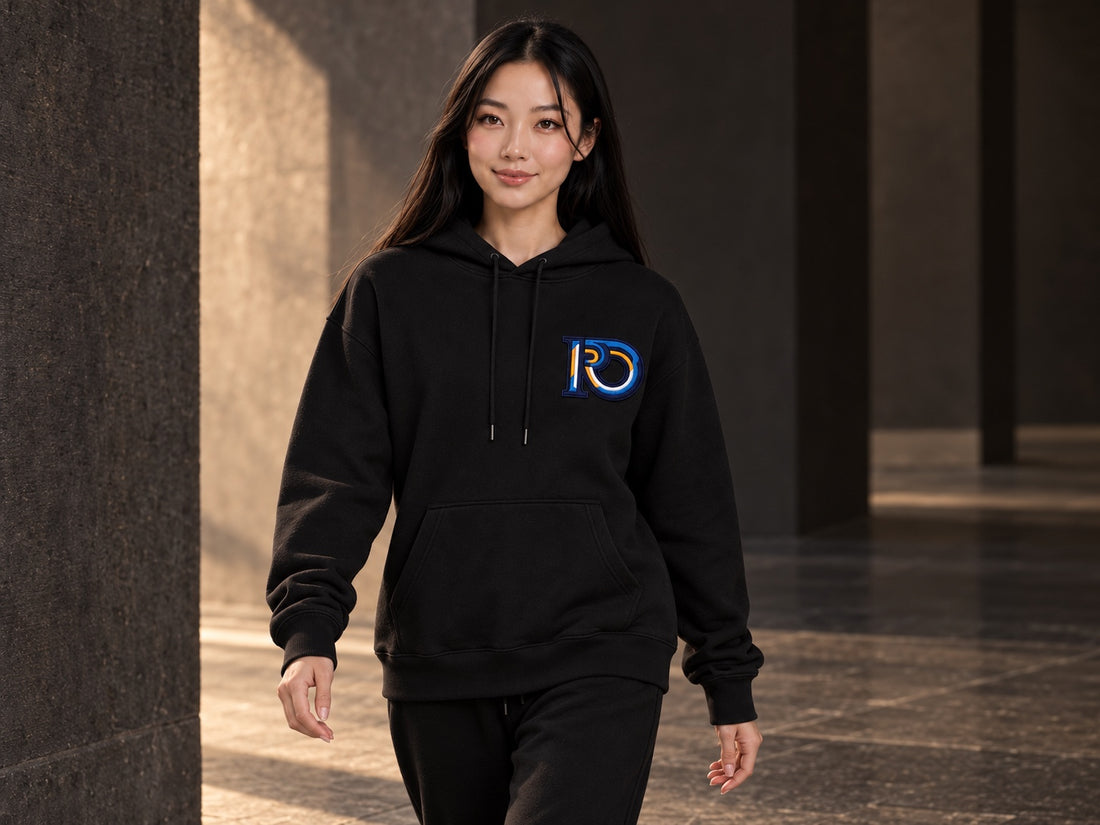 Model walking in an R10 Monogram hoodie, showing its sleeves, body, cuffs, and hem.