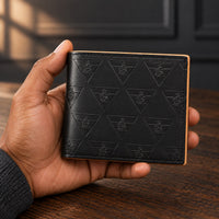 The closed black R10 Leão Branco wallet held in one hand above a wooden desk.