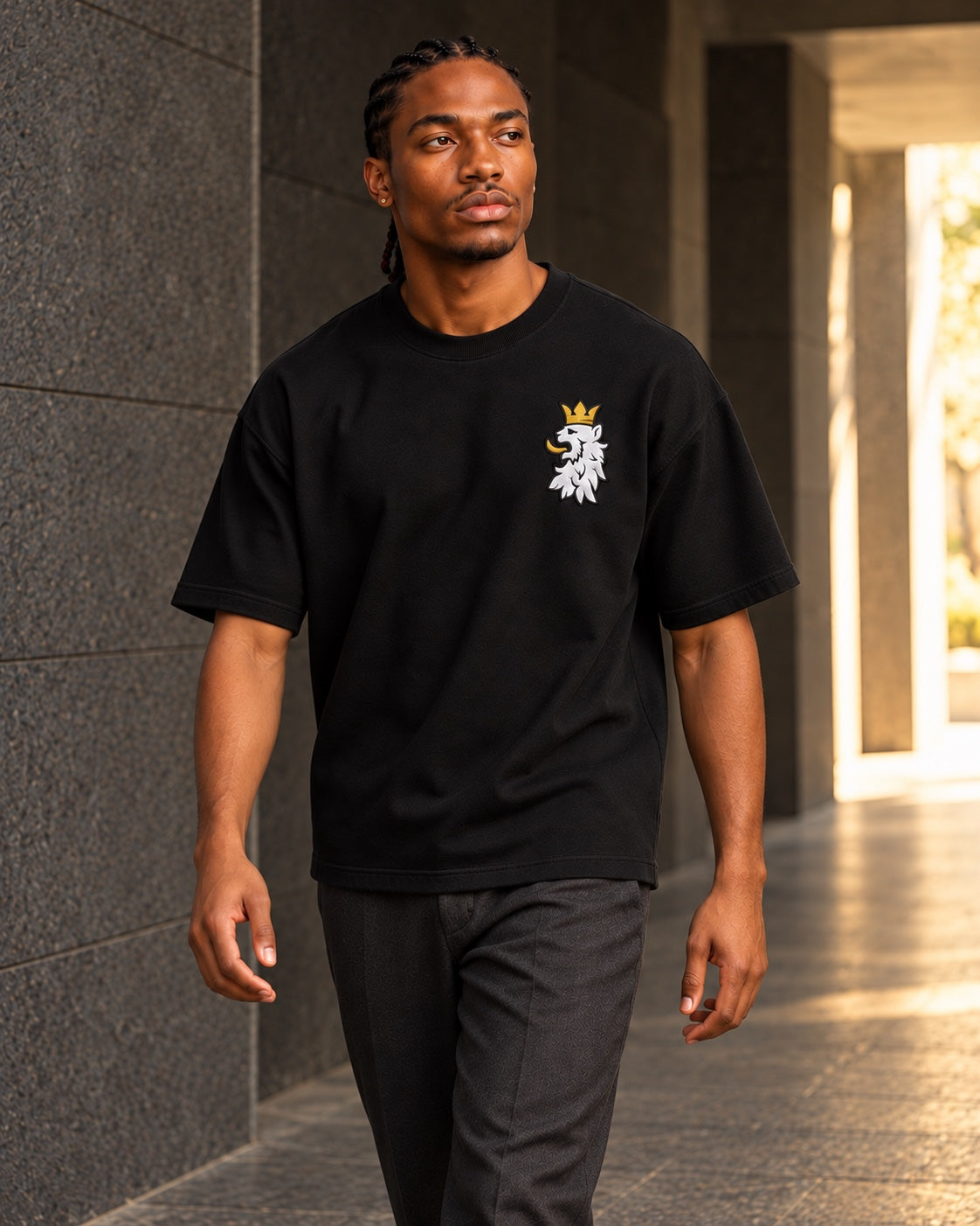 Black R10 Leão Branco Motif Tee — worn walking through a stone passage.