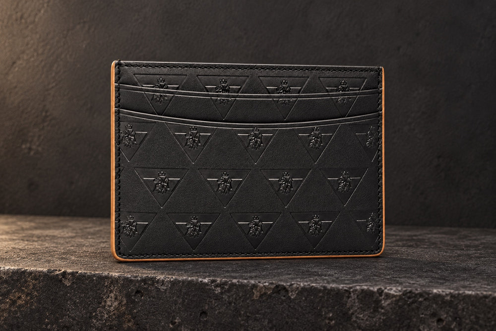 Black R10 Leão Branco cardholder on a stone ledge, showing its front slots, embossed motif, and stitched perimeter.