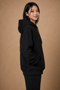 Side profile of the R10 Monogram Hoodie showing the relaxed fit, structured hood, and heavyweight drape.